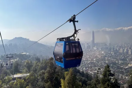 an image of a cable car going up a mountain with a cityscape and mountains behind