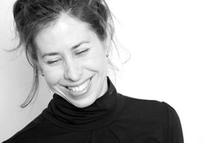 Black and white portrait of Amy Neswald, smiling with closed eyes.