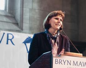 Kim Cassidy standing behind a podium with a Bryn Mawr banner in the background