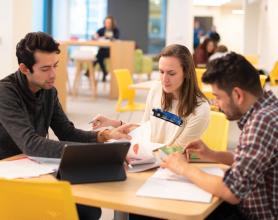 Three students sitting around a table studying