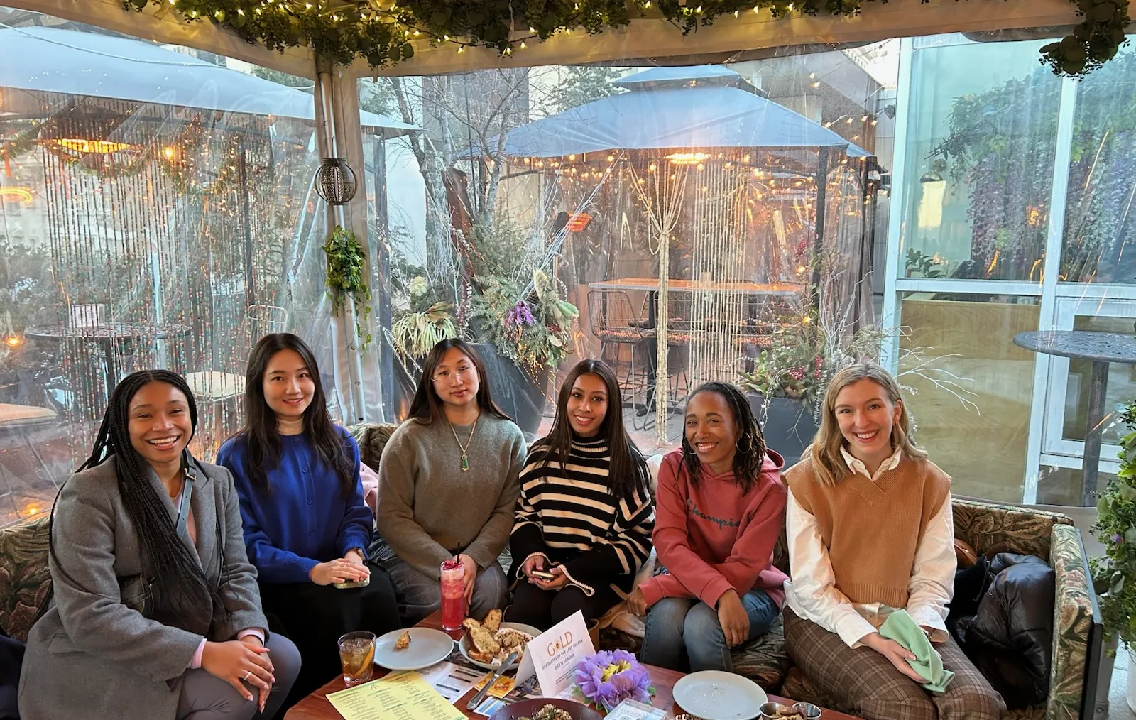 Smiling GOLD alums sitting at a restaurant table.