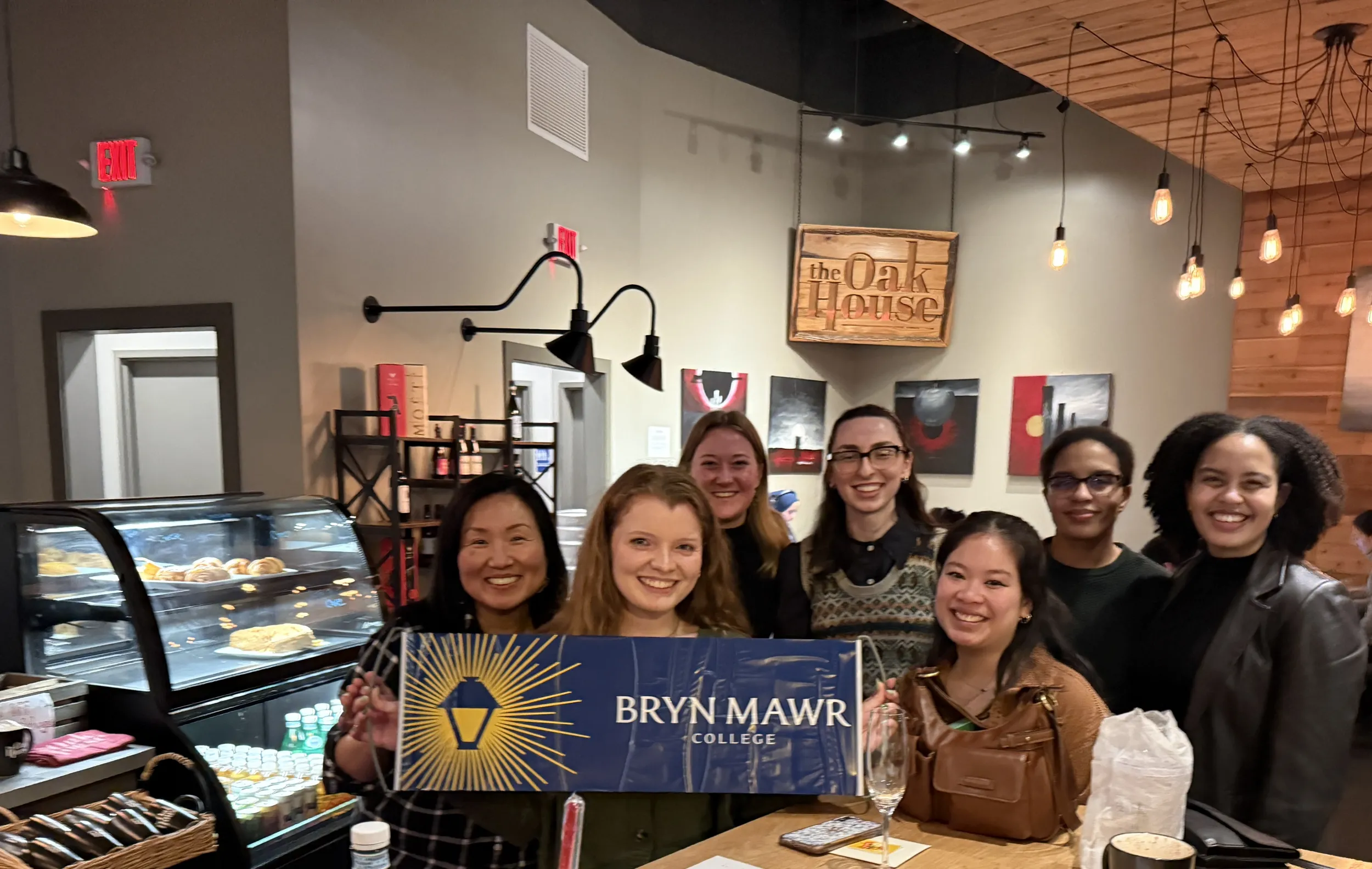 Smiling GOLD alums holding a Bryn Mawr College banner.