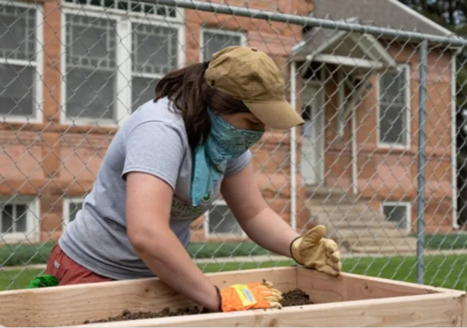 A person working with a raised garden bed.