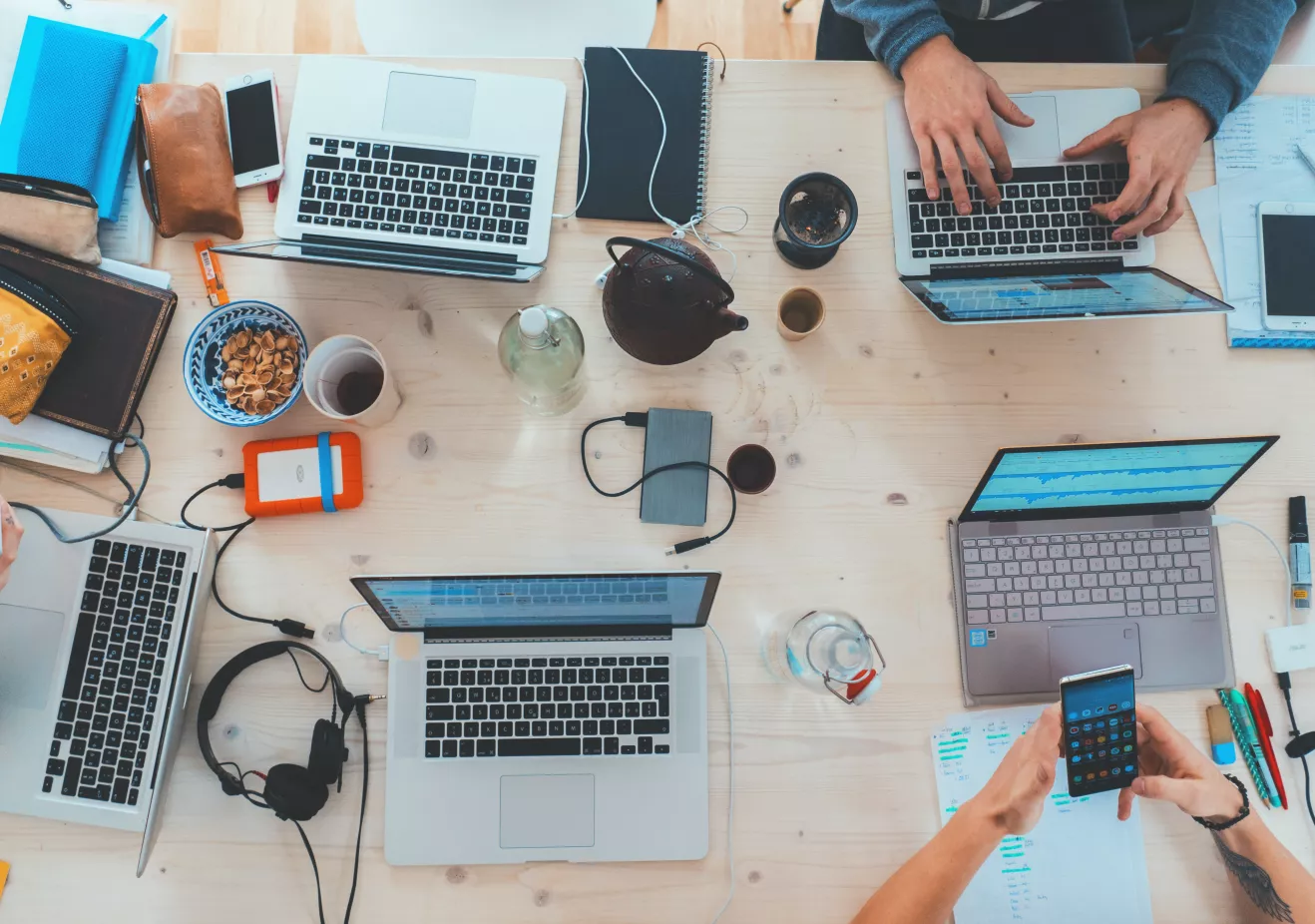 People sitting around a table top with different electronic, hearing and writing tools on it. 