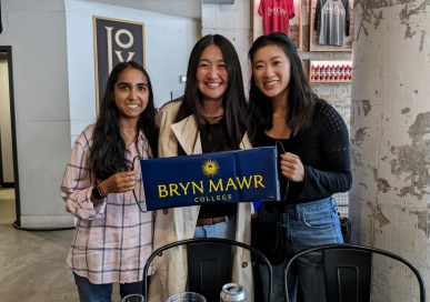 Three GOLD alums pose with a blue banner that says Bryn Mawr College.