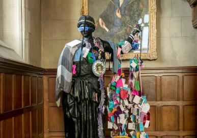 Statue of Athena covered in trinkets and paper chains. 