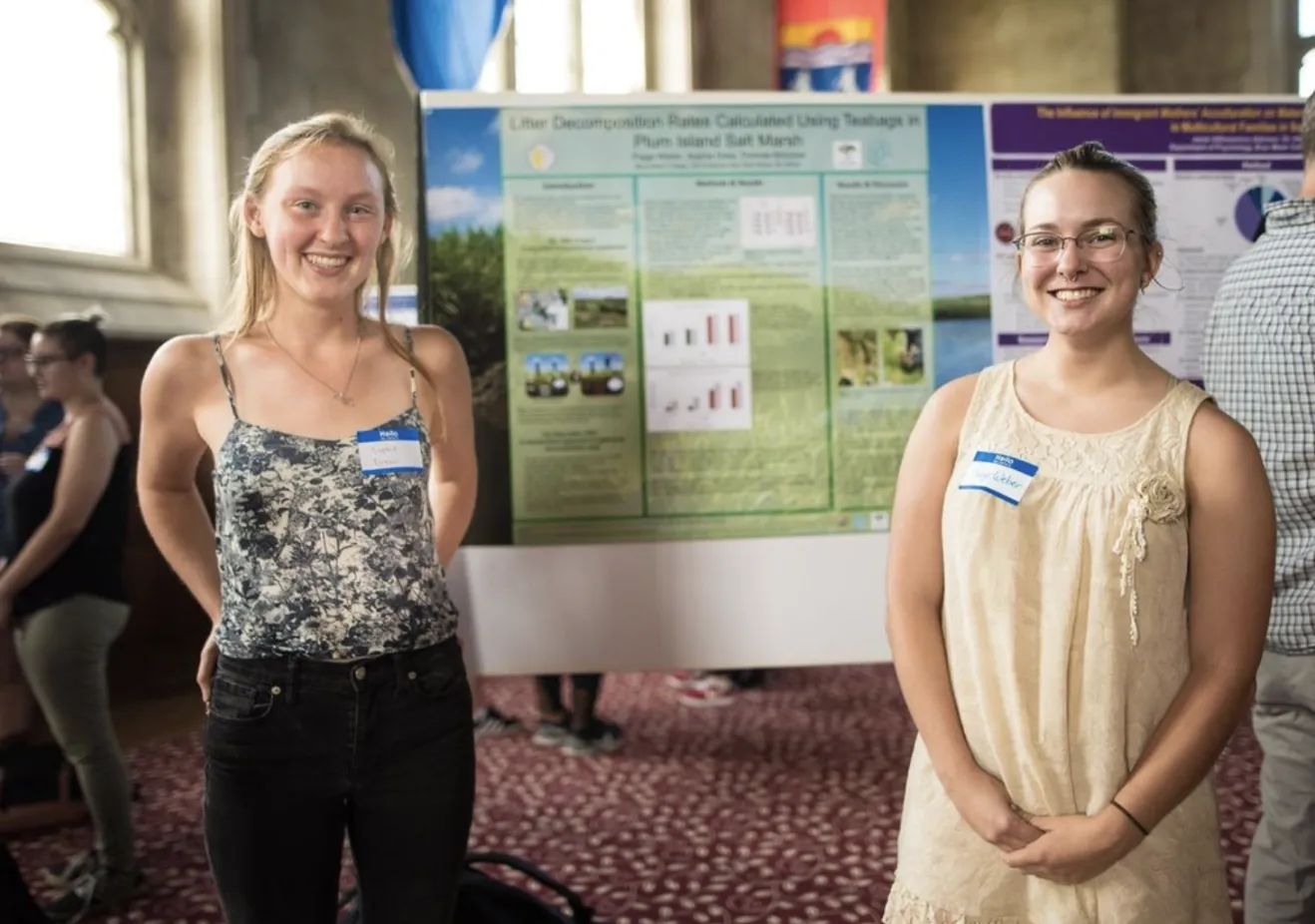 Two students smiling in front of a research poster in the Great Hall