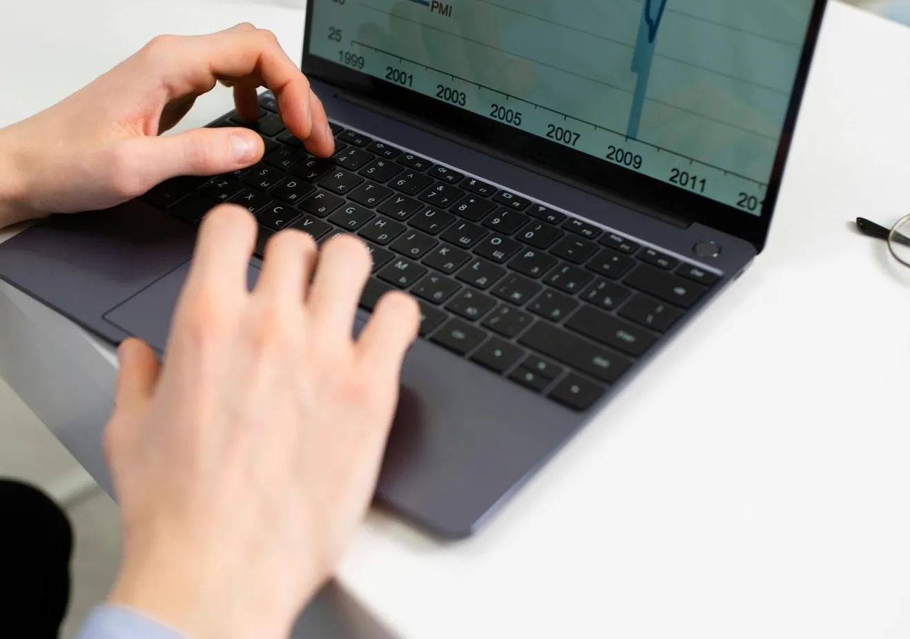 Typing on a laptop with a chart on the screen