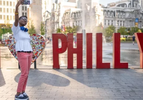 Person taking photo in from of "PHILLY" sign