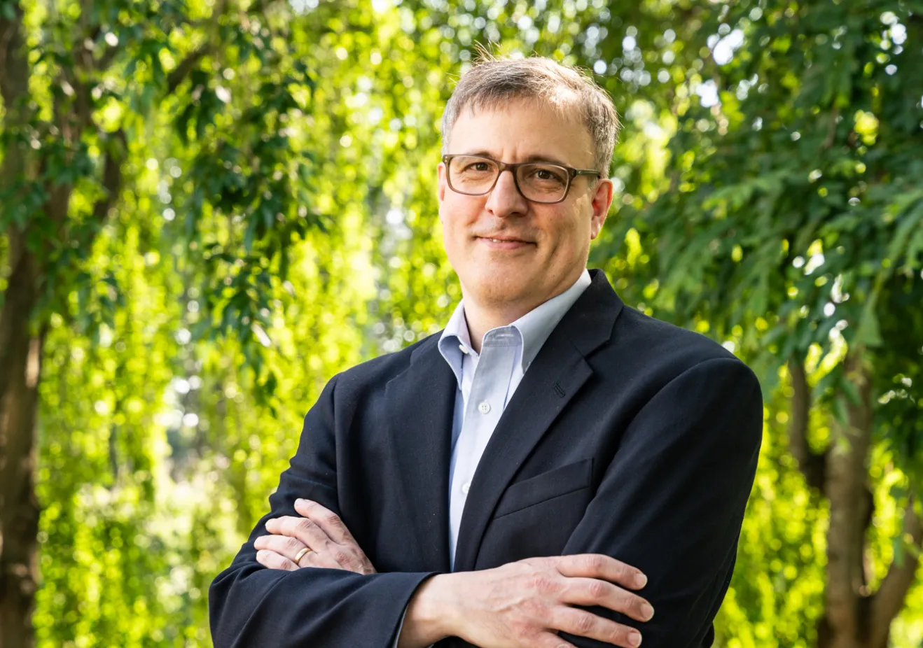 man in dark suit in front of trees