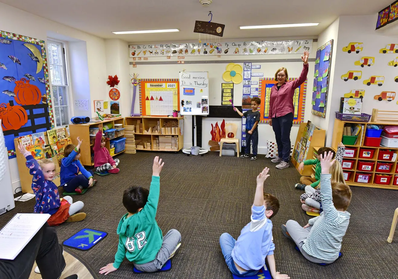 small kids raising their hands in a circle