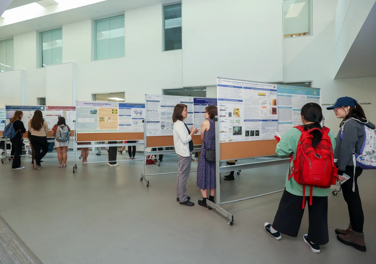 Several presentation boards are lined up in Park Science atrium and people walk between them