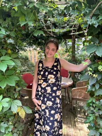 Katie Manyin standing under a vine arch. 