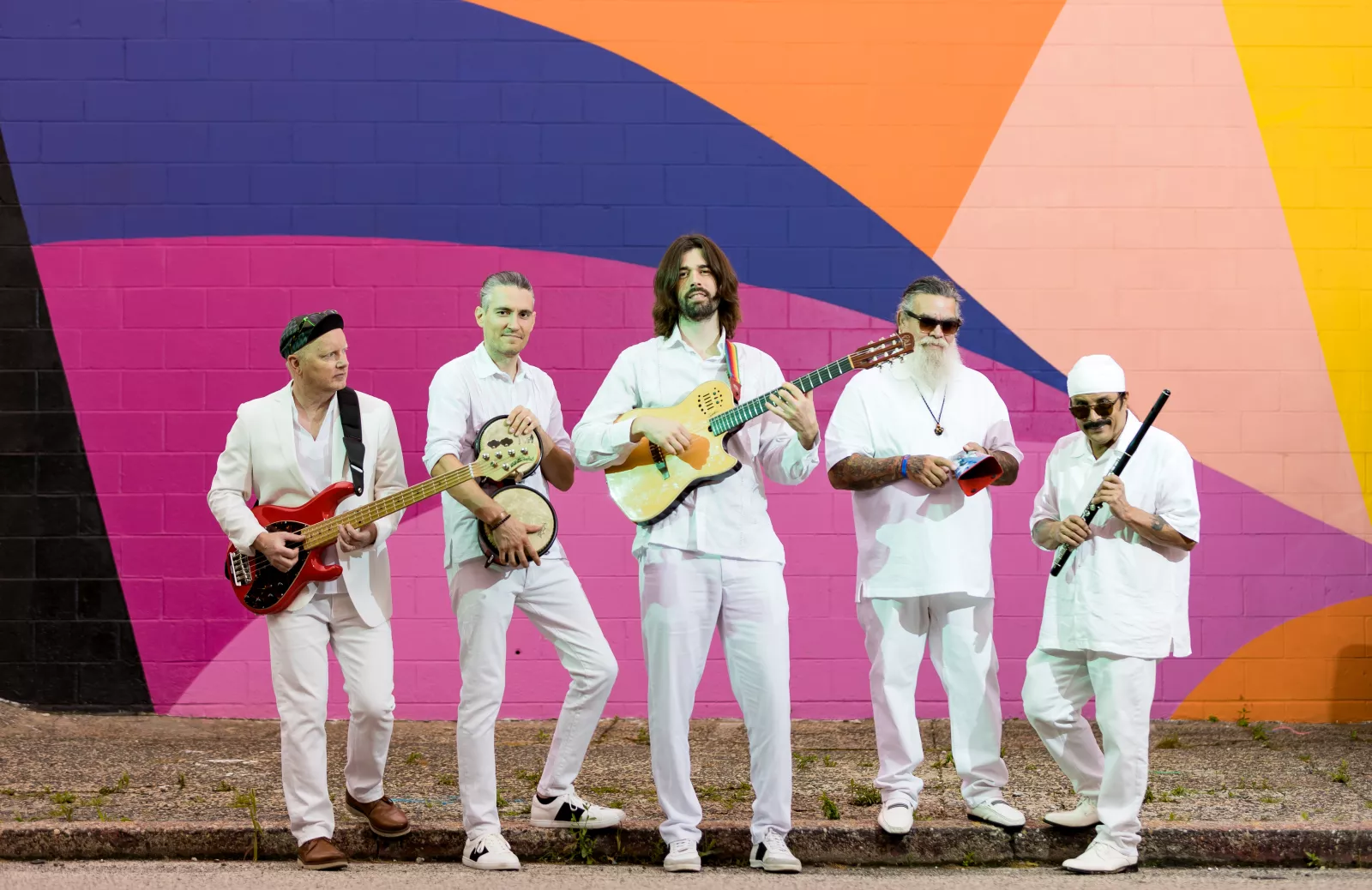 De Tierra Caliente band stands in front of colorful wall