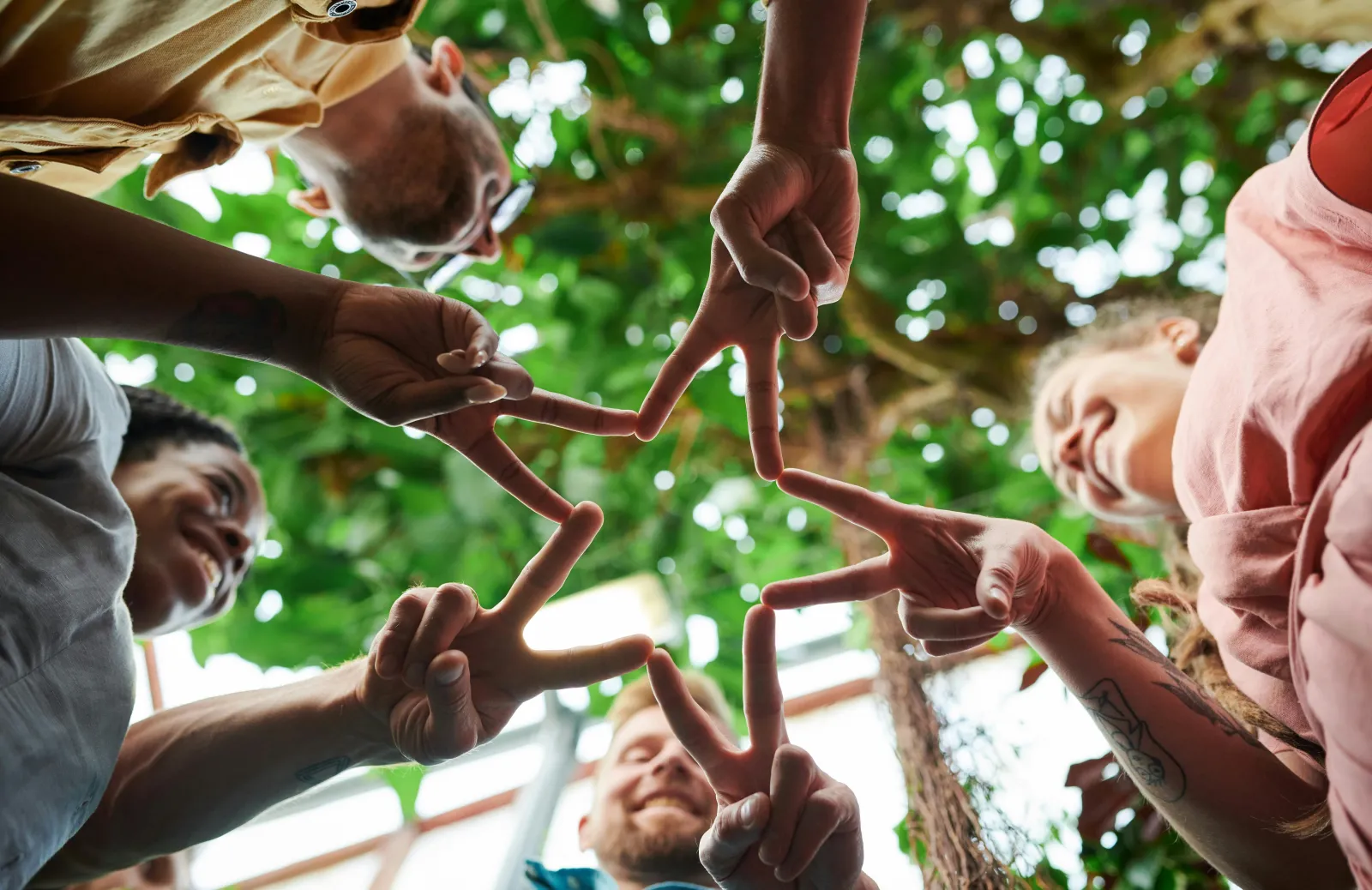 People in a circle join their hands together to create a star shape