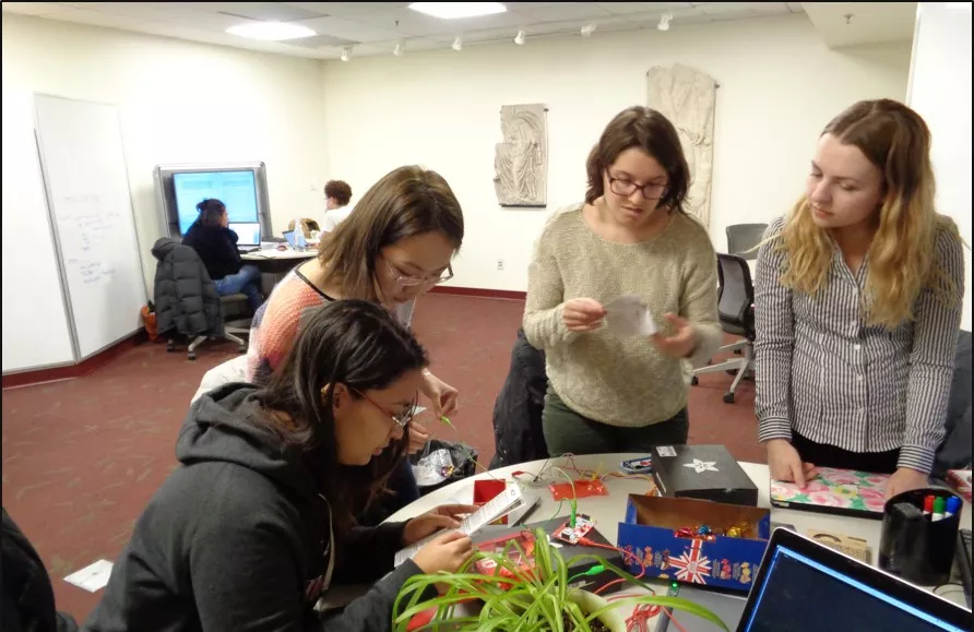Four students with wires and a plant.