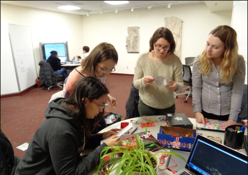 Four students with wires and a plant.