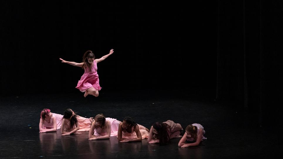 Image of dancers on stage; one dancer is jumping