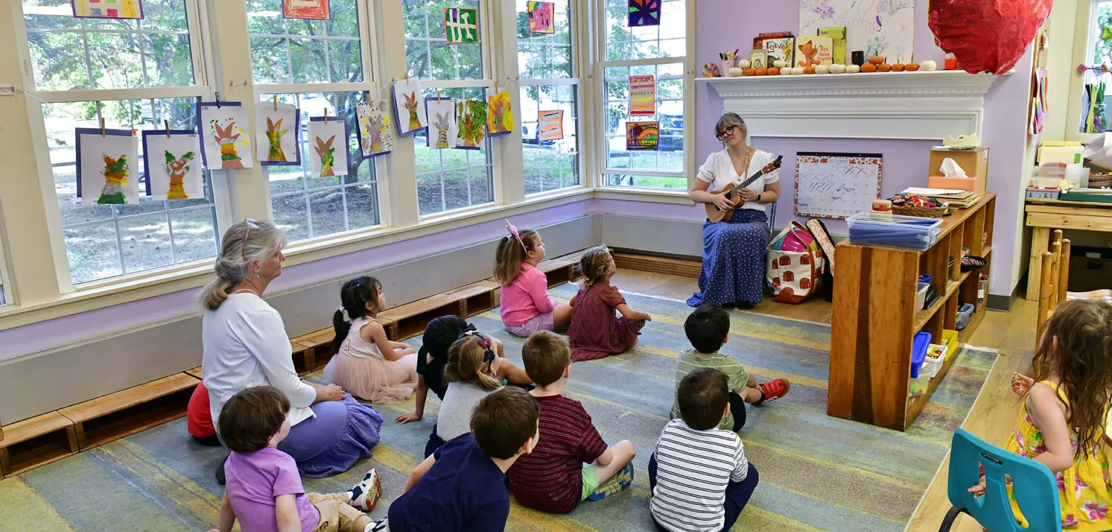 Students listening to a teacher playing guitar