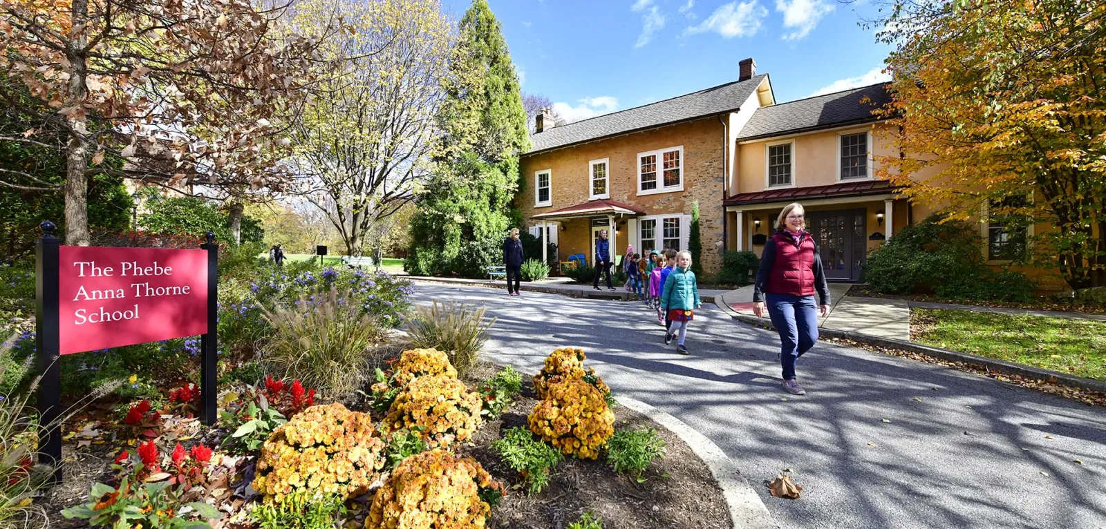 Small kids walking behind their teacher