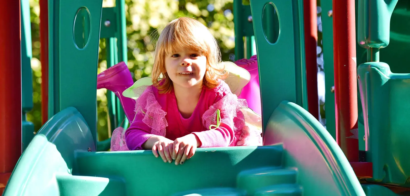 Girl dressed in pink on green slide