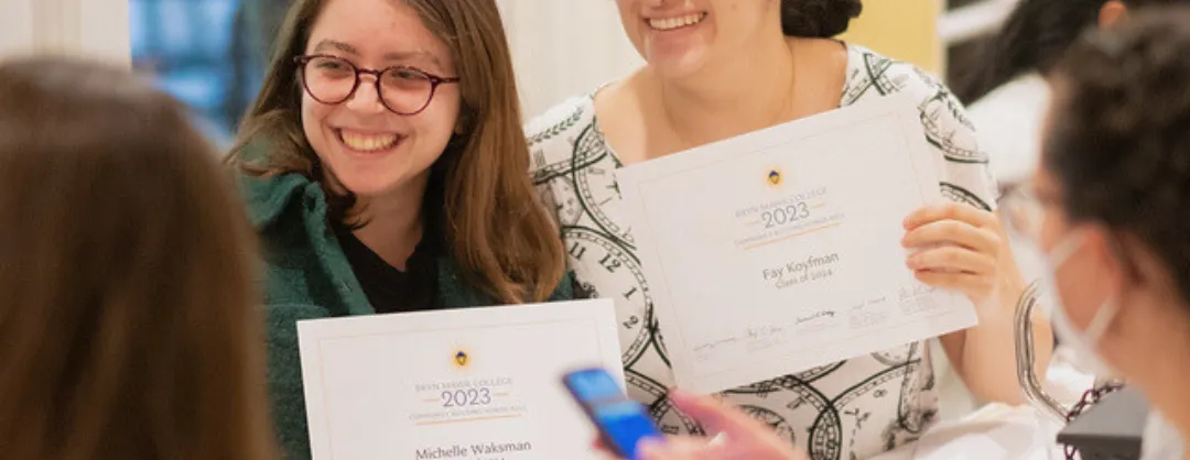 Students smiling holding an award paper.