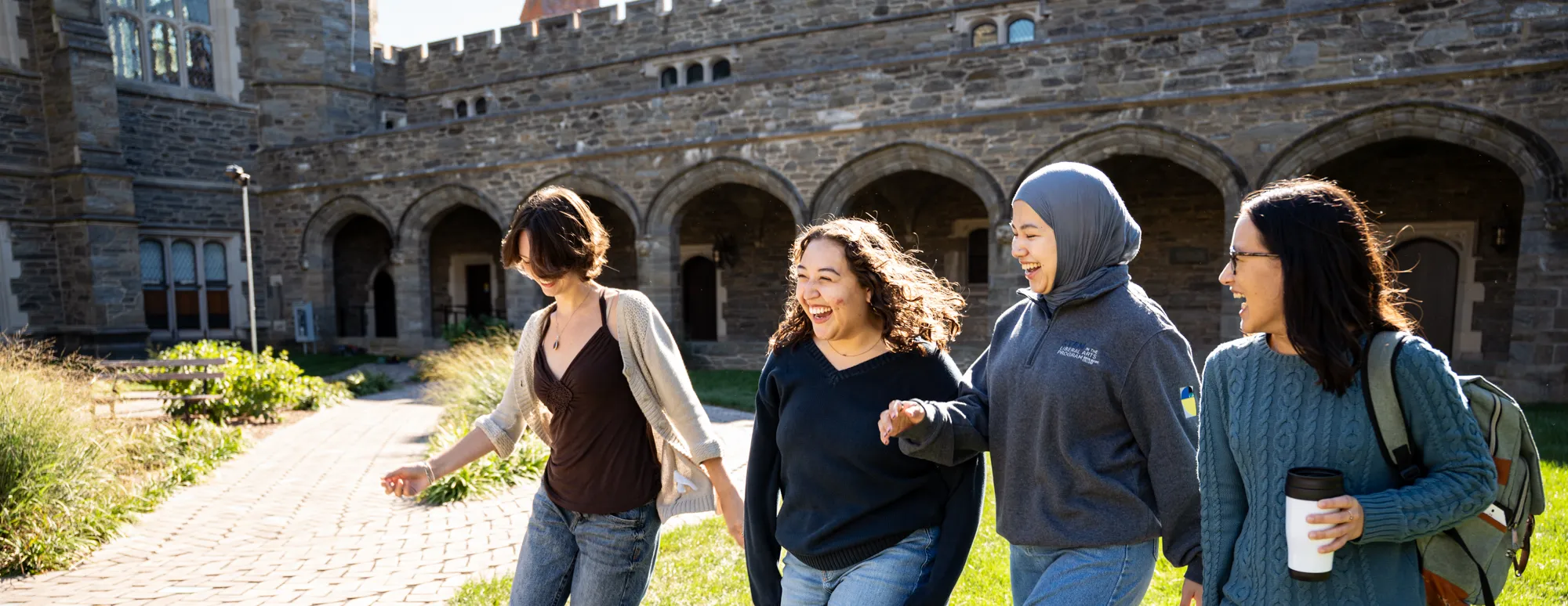 Students walk through the Cloisters on a sunny day.
