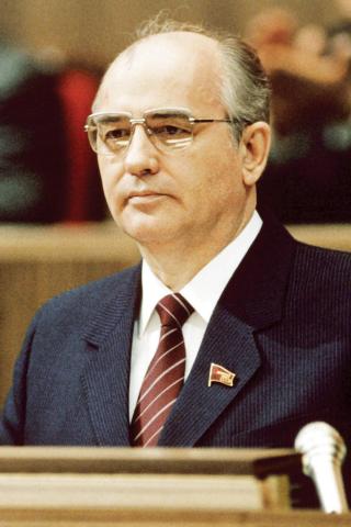 Mikhail Gorbachev seated behind microphones