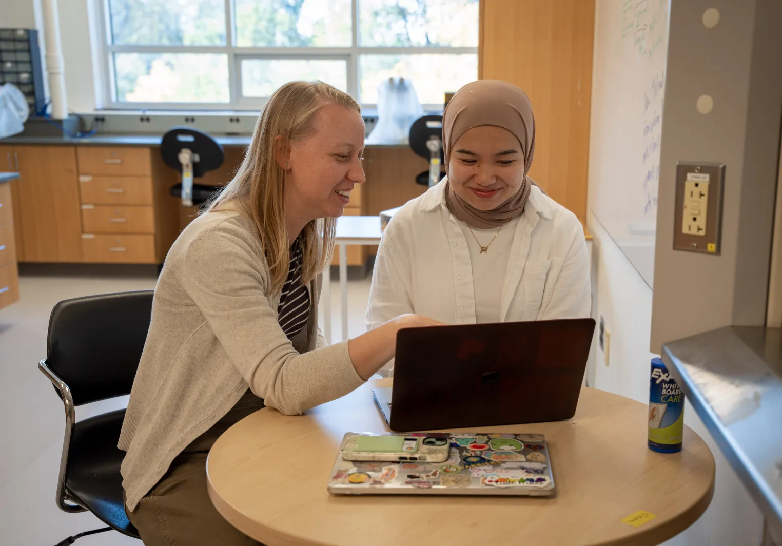 Weber and students sitting at a computer and smiling