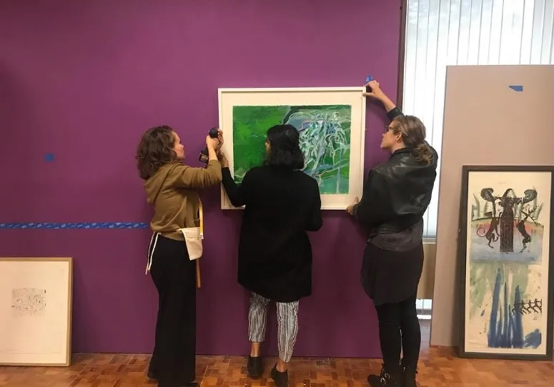 Three student curators install work of art in 1912 Gallery of Canaday Library
