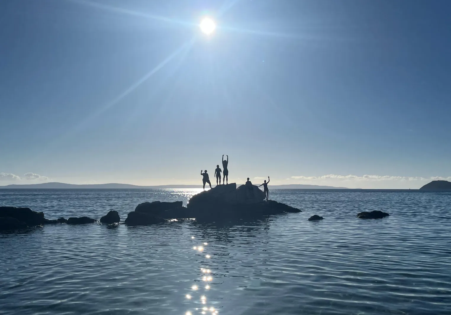Katie and her friends posing on a rock in the ocean