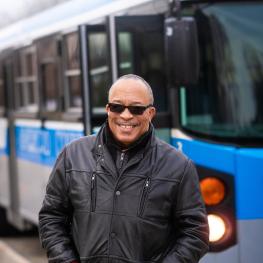 Steve Green smiling and posing in front of the Blue Bus