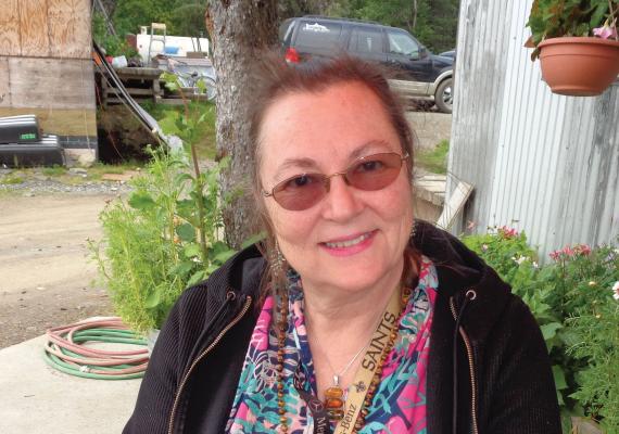 Amy L. Sandridge seated in front of the Wood River Market, smiling and wearing a black jacket.