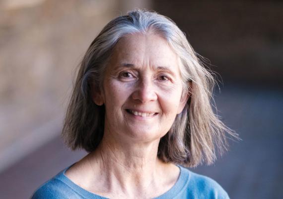 Kathy Tierney stands with arms crossed, smiling, wearing a blue shirt