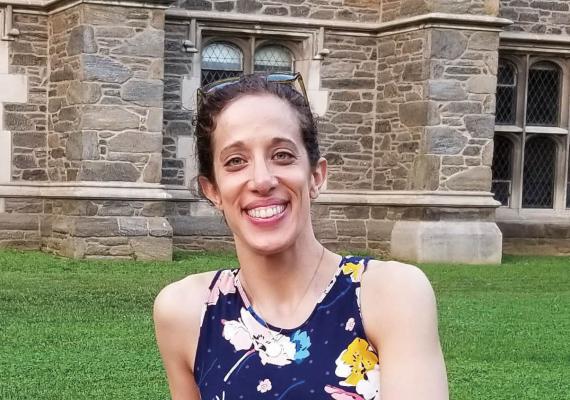 Marissa Patterson sitting on a short stone wall in a floral dress