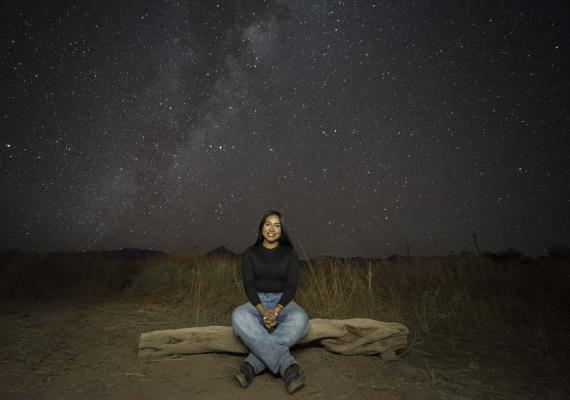 Nelid sitting under a sky full of stars. 