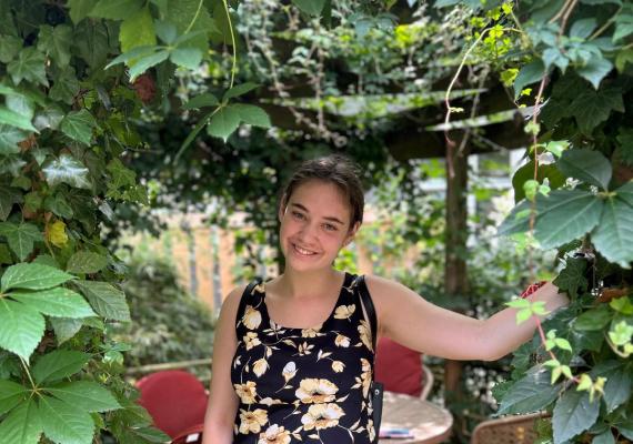 Katie Manyin standing under a vine arch. 