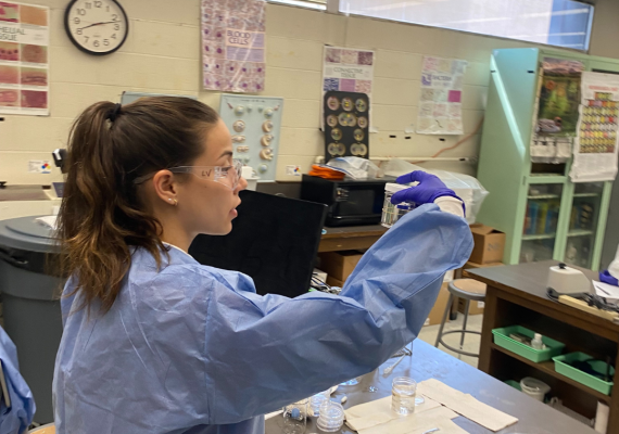 Leila in a lab coat and goggles