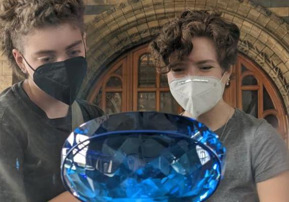 Two students observe a large blue gem