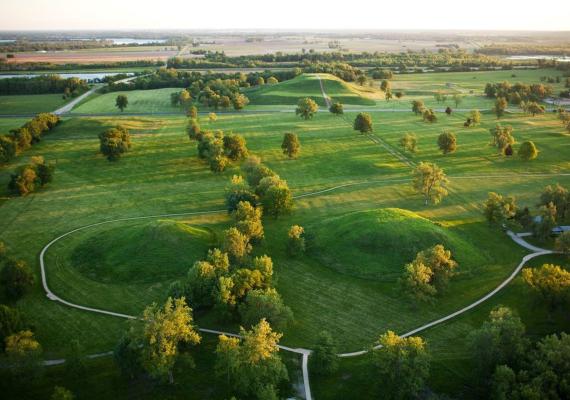 Photograph of Cahokia, showing pathways around two hills with woods in the foreground.