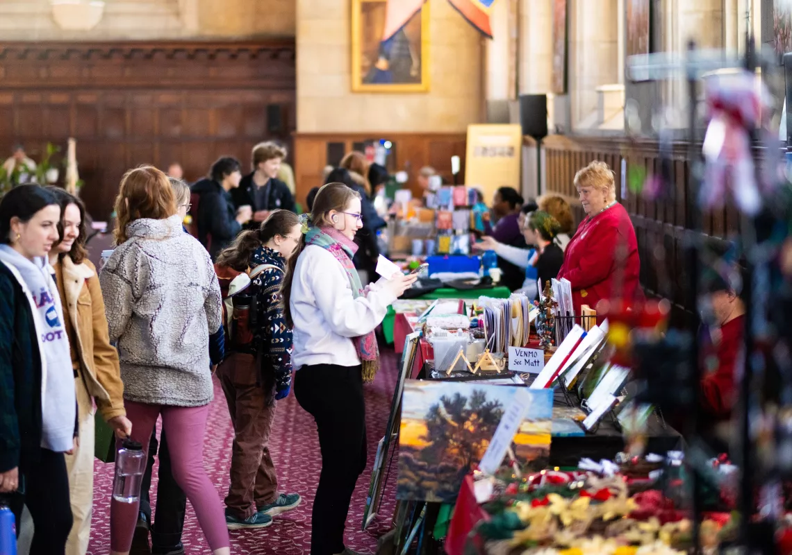 People interacting with holiday vendors in Great Hall