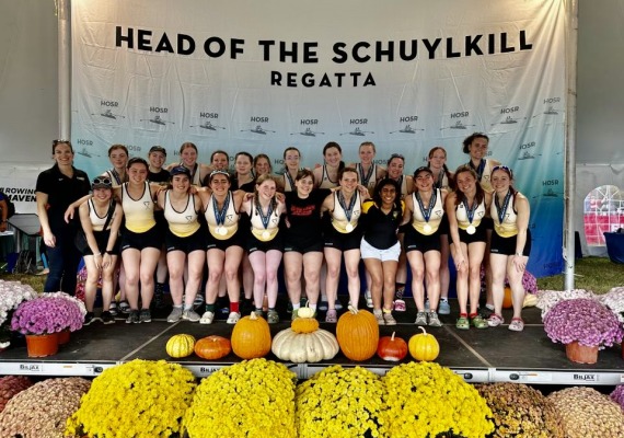 Group photo of the Rowing team in front of the "Head of The Schuylkill" Photo Banner