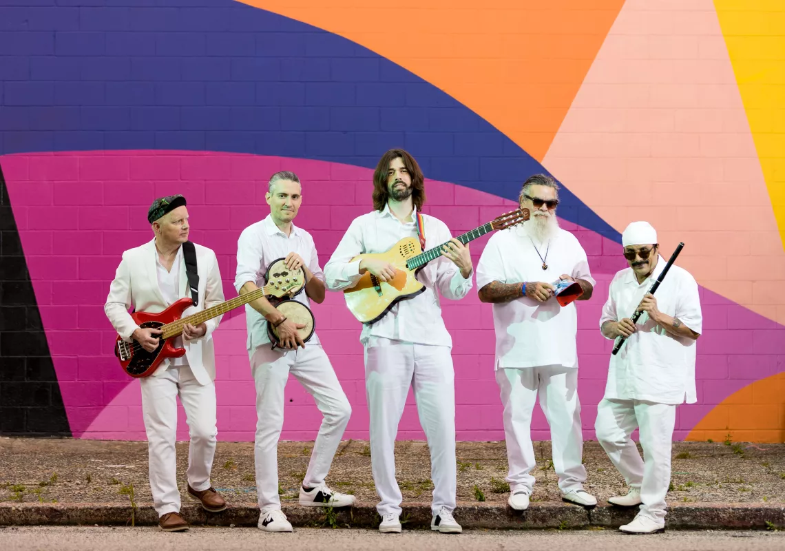De Tierra Caliente band stands in front of colorful wall