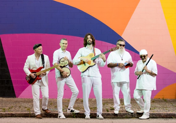 De Tierra Caliente band stands in front of colorful wall