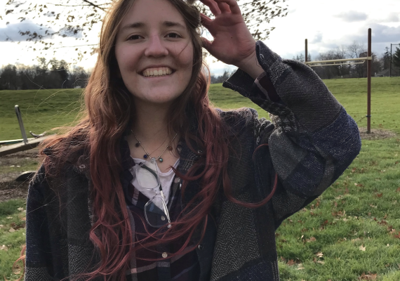 Headshot of Cate Elam '25 standing in front of a field