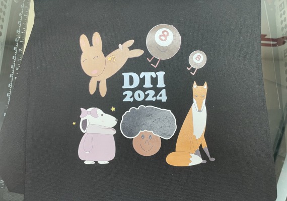 Black tote bad with "DTI 2024" written on it, as well as symbols developed by each of the five interns