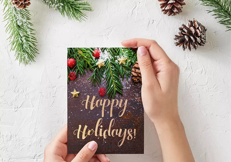 Hands holding a card that reads Happy Holidays