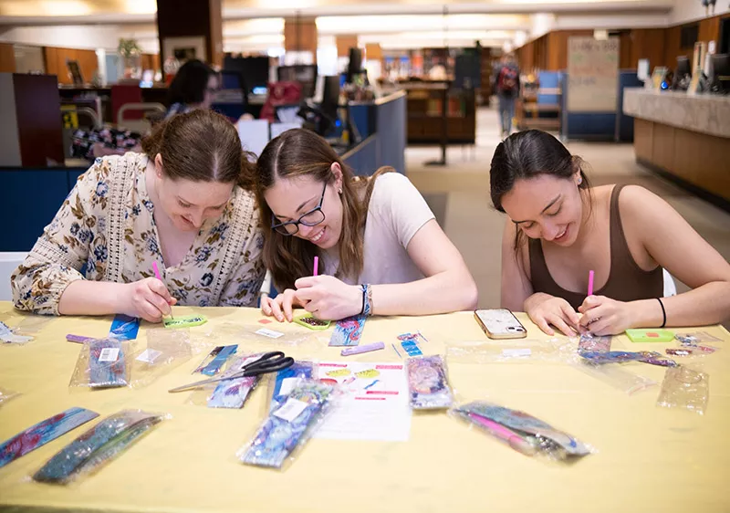 Students bedazzling bookmarks in library