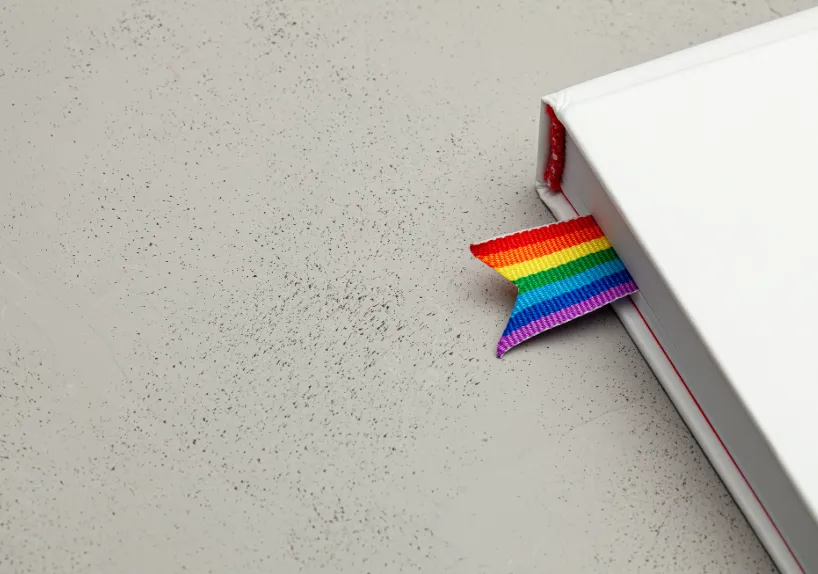 A white book, with a rainbow ribbon as a bookmark