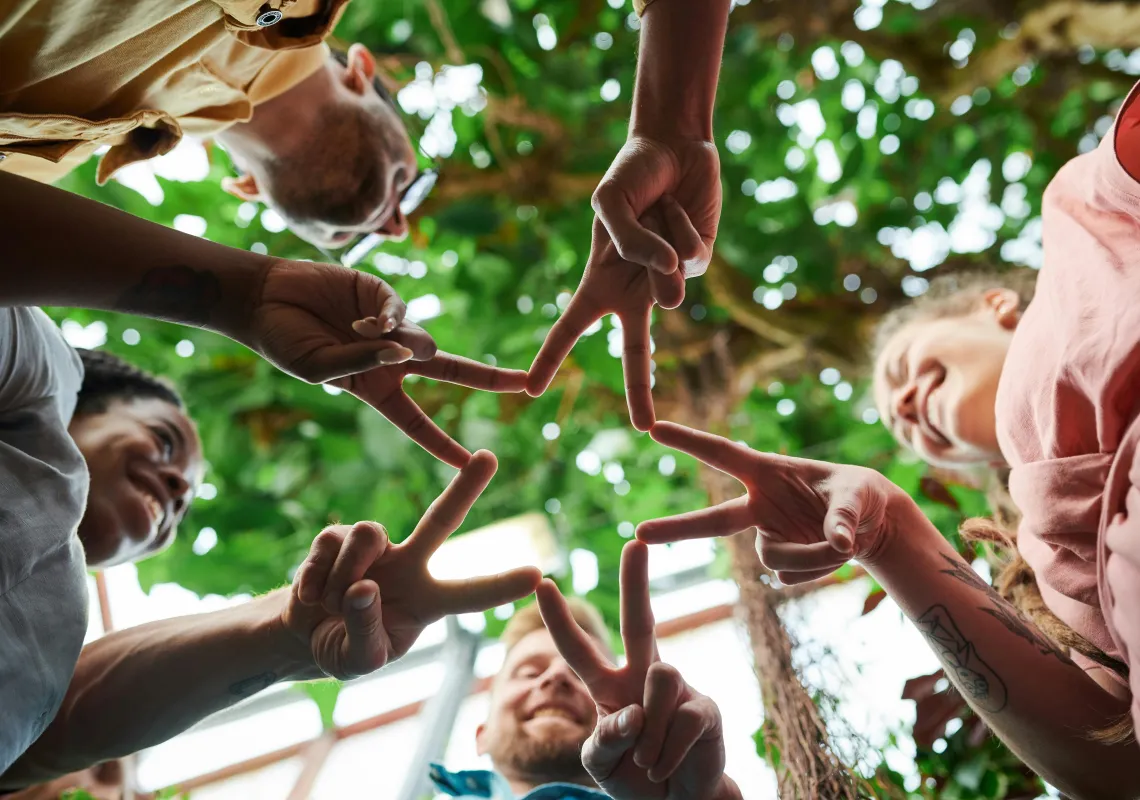 People in a circle join their hands together to create a star shape